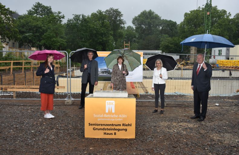 Gruppenbild nach Grundsteinlegung mit Abstand und Regenschirm (von links): Susanne Bokelmann, Ossi Helling, Henriette Reker, Gabriele Patzke und Thomas Brauckmann