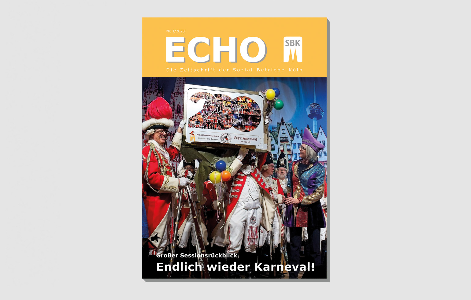 Das Titelbild der Echo-Ausgabe Nr. 1 2023 zeigt SBK-Geschäftsführerin Gabriele Patzke bei der Übergabe einer Collage an Günther Hunold, den Präsidenten der Roten Funken bei der Karnevalssitzung für die SBK-Werkstätten.